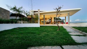 A modern building with a covered outdoor area, a grassy lawn, and a pathway leading to the entrance. - Villa Bliss (Kuta)