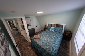 Een slaapkamer met een bed, een kaptafel, een nachtkastje en een raam.