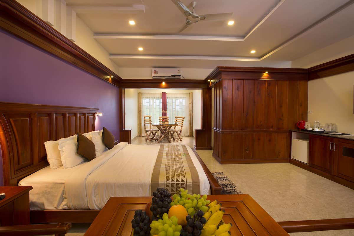 A hotel room with a bed, a dining area, and a kitchenette.