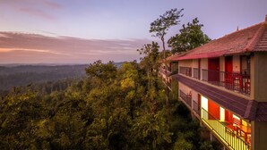 Hotel met een balkon, met uitzicht op het omliggende bos en heuvels in de verte.