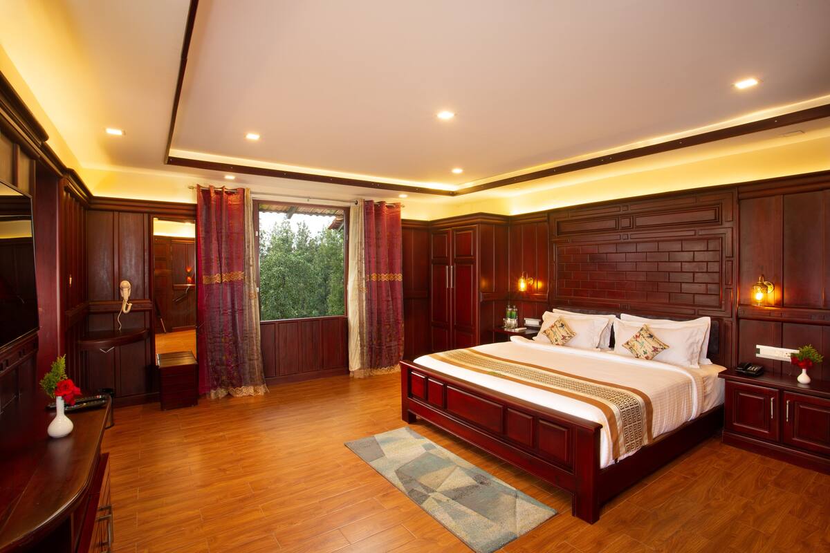 A spacious bedroom with a large bed, wooden flooring, and built-in wardrobes.