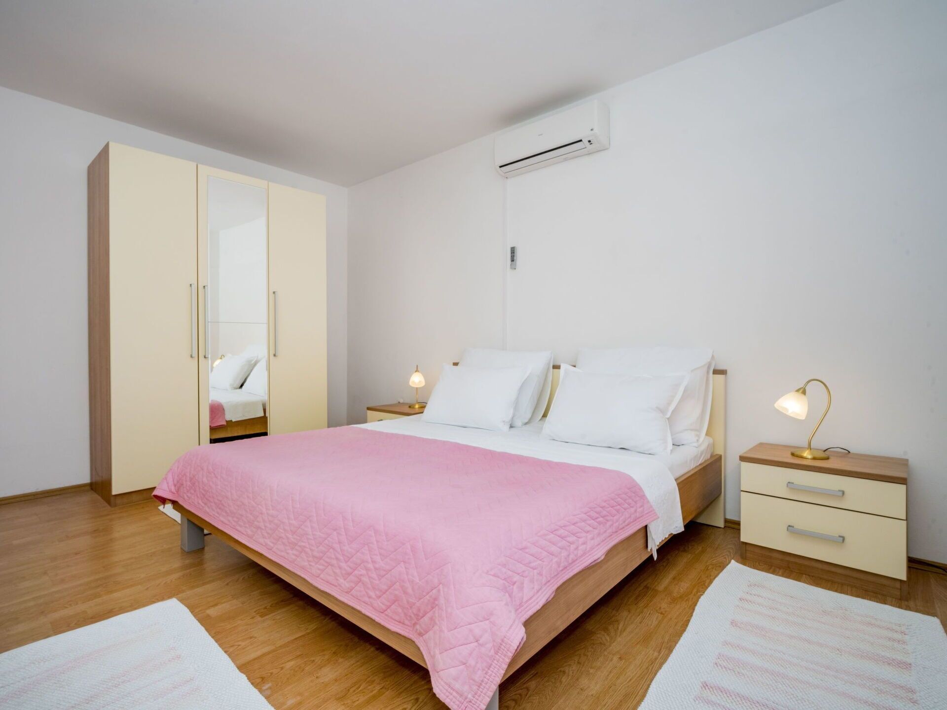 Une chambre à coucher comprenant un lit, des tables de chevet, une armoire et un appareil de climatisation.