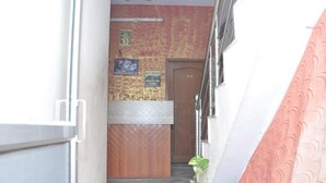 Un couloir étroit mène à un espace d’accueil doté d’un comptoir en bois et d’une porte.