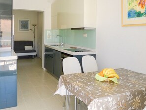 Une cuisine compacte avec un coin repas, un canapé et une petite table sur laquelle sont disposés des fruits.