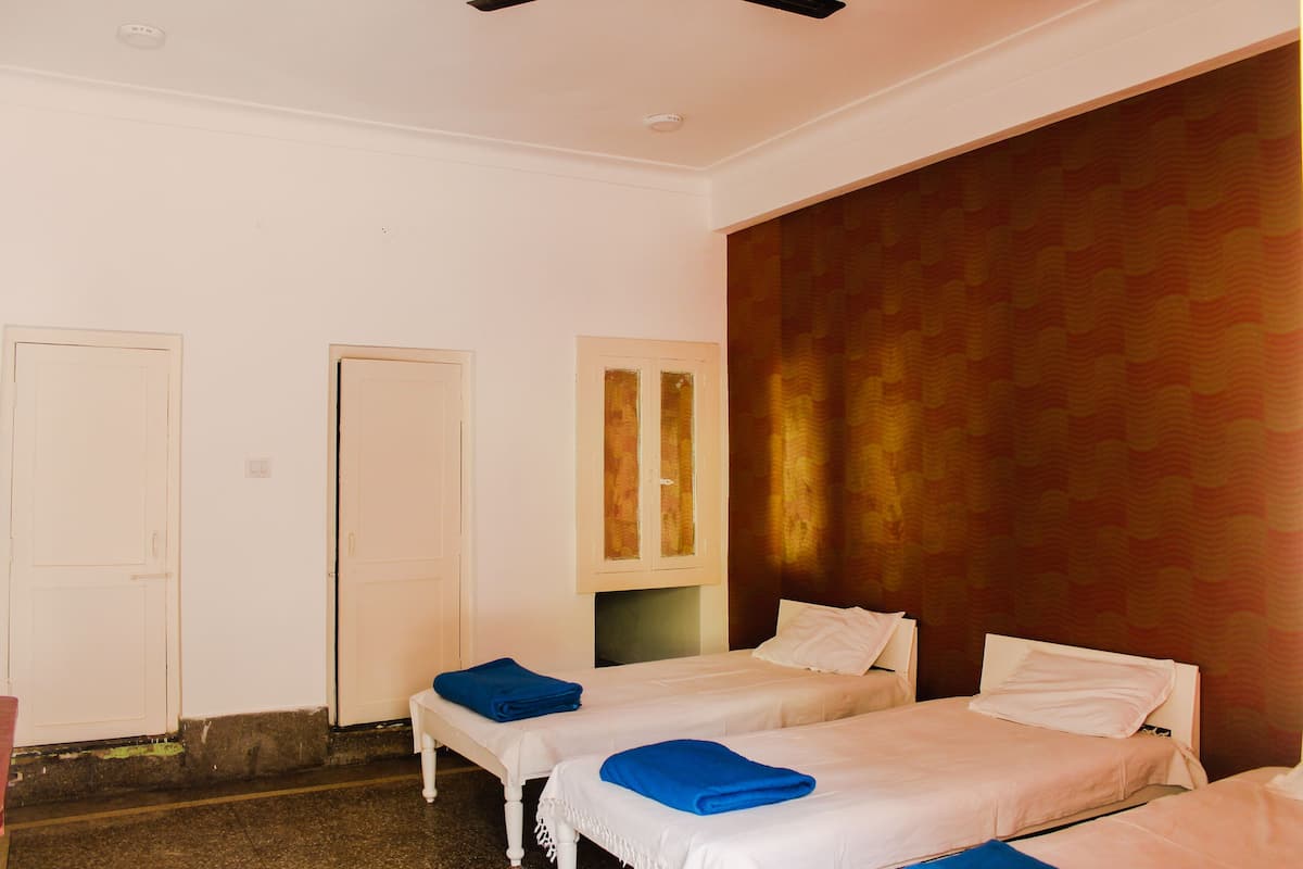 Quarto de hotel com duas camas de solteiro, um guarda-roupa e uma porta.