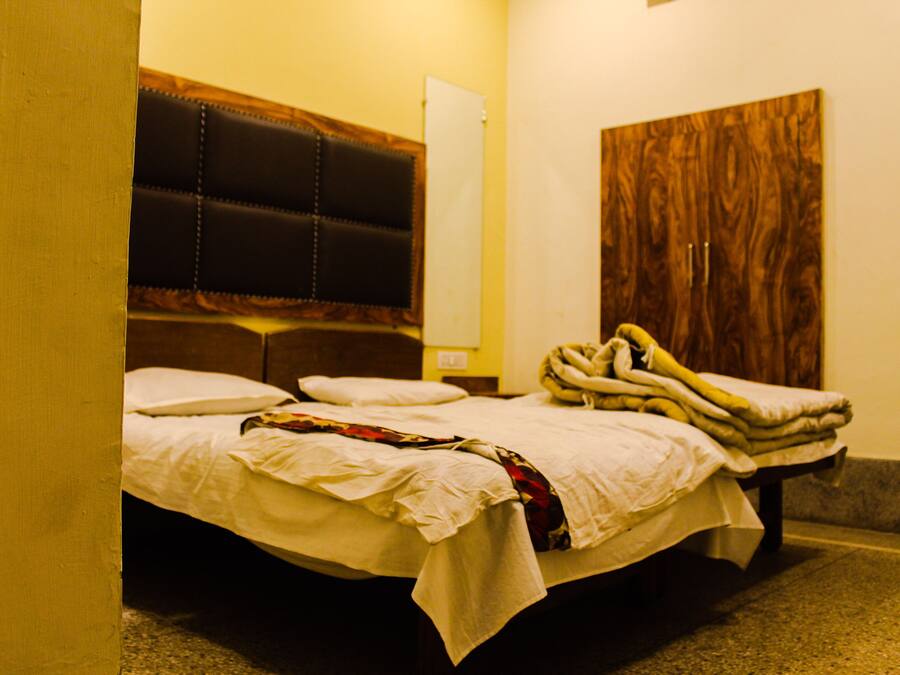 Quarto de hotel com cama, cabeceira de madeira e guarda-roupa.