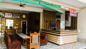 Un hall de hotel con mostrador de recepción, zona de estar y un reloj en la pared.