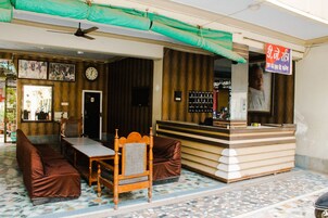 A hotel lobby with a reception desk, seating area, and a clock on the wall.