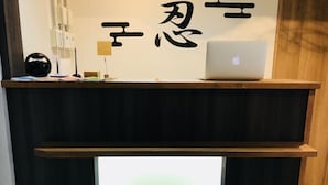 A reception desk with a laptop, a black speaker, and a sign with Japanese characters. - bnb+ Ninja Otsuka - Hostel (Tokyo)