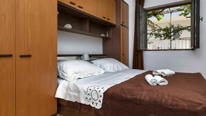 Une chambre à coucher avec un lit, une fenêtre donnant sur des arbres et des meubles en bois.