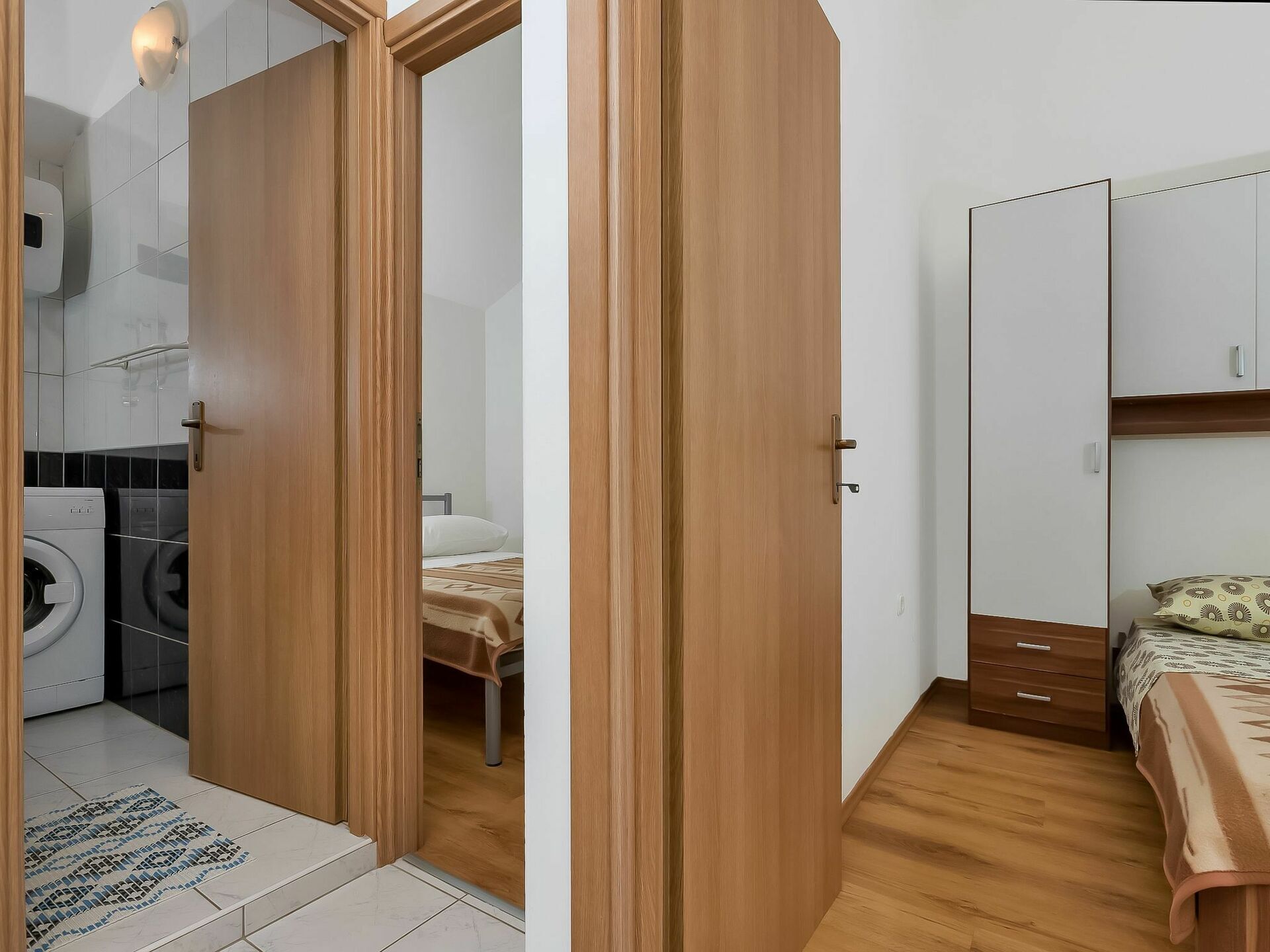 Ein Schlafzimmer mit einem Holzschrank, einem Bett mit gemustertem Überwurf und einem kleinen Nachttisch.