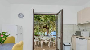 Une cuisine avec un coin repas, une horloge au mur et une vue sur un arbre et l’eau à l’extérieur.