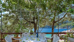 Un espace de restauration en plein air avec une table recouverte d’une nappe à motifs de citron, entourée de chaises blanches.