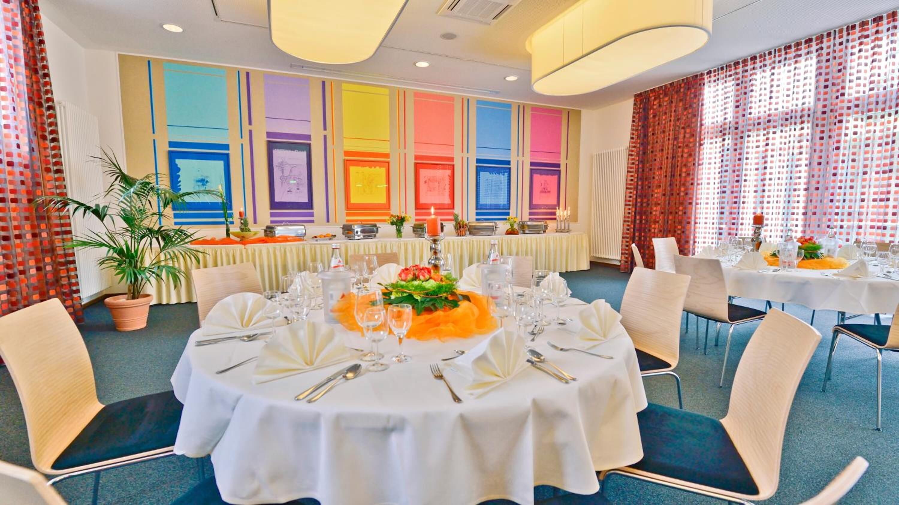 Un espace repas avec des tables rondes dressées pour le repas, agrémenté de nappes blanches, de couverts en argent et de verres.