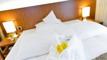 Ein Hotelzimmer mit einem großen Bett, zwei Nachttischlampen, einem Gemälde an der Wand und einem Handtuch mit gelben Blumen auf dem Bett.