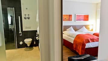 A hotel room with a shower, toilet, and bed.