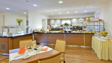 A modern hotel dining area with a central buffet, wooden furniture, and a clean, well-lit environment.