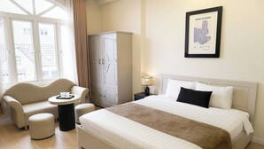 A hotel room with a large bed, a sofa, a small table, and a wardrobe. - Ngoc Trai Vang Hotel (Xuan Huong - Da Lat)