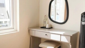 A small, neatly arranged bedroom with a white desk, a chair, a mirror, and a heater. - Ngoc Trai Vang Hotel (Xuan Huong - Da Lat)