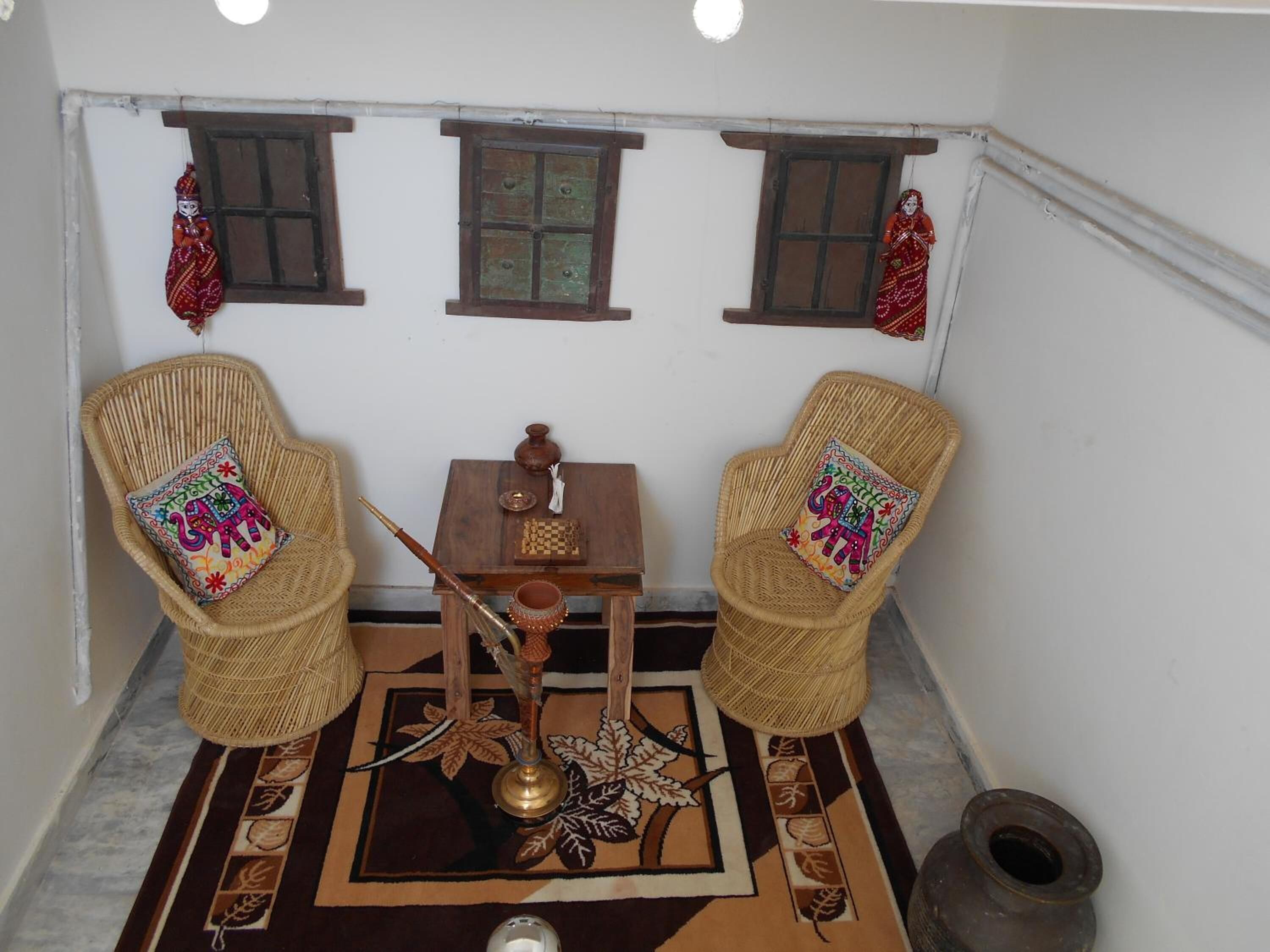 A small, cozy room with two wicker chairs, a small table, and a decorative rug.