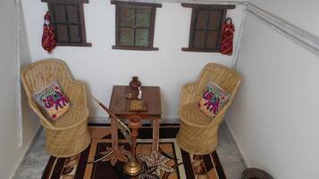 A small, cozy room with two wicker chairs, a small table, and a decorative rug.