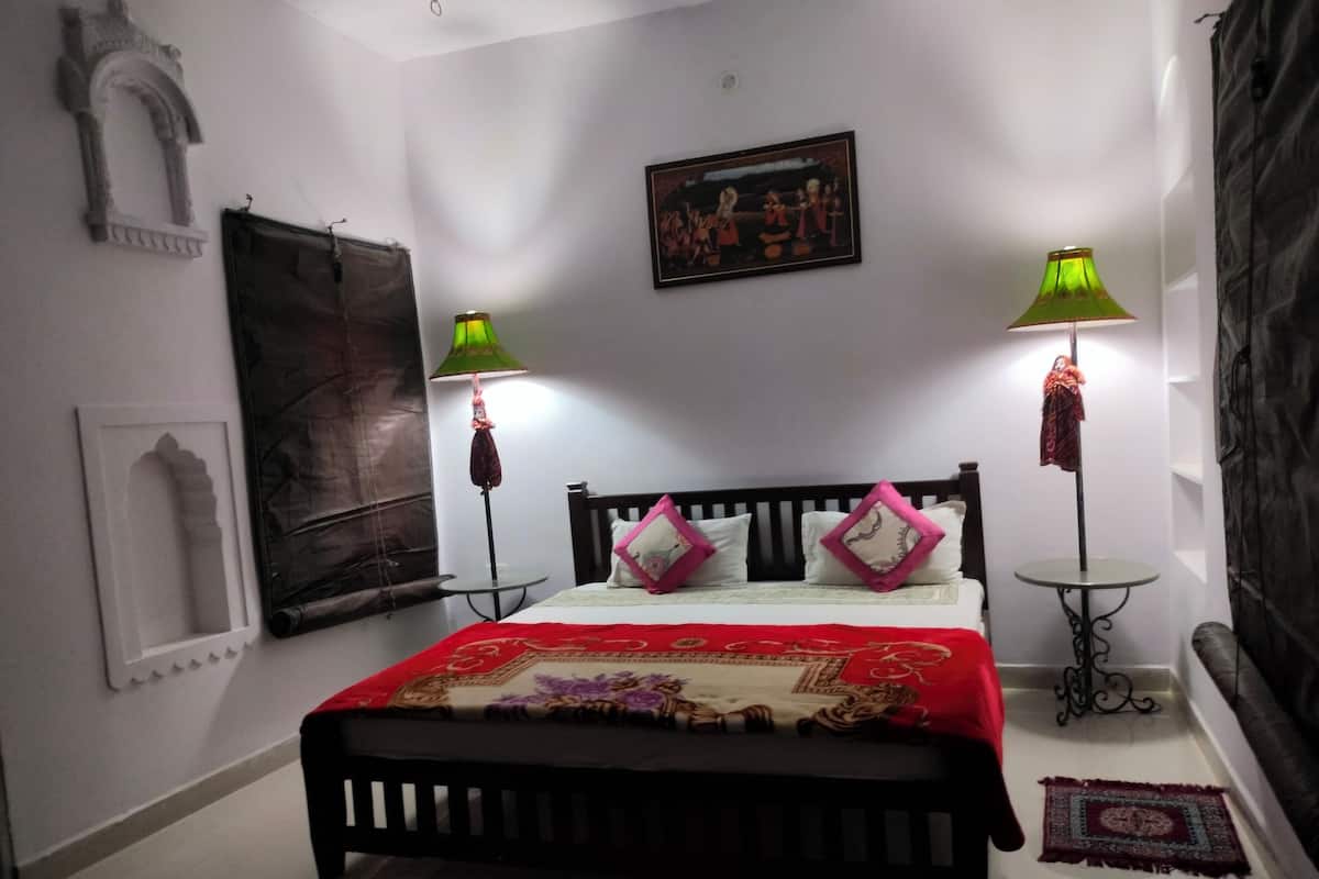 Un dormitorio con cama, dos lámparas, un cuadro y un arco decorativo.