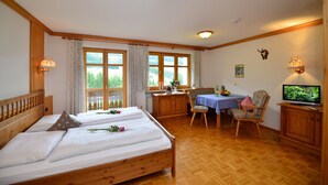 A bedroom with a wooden bed, a dining table with chairs, and a television. - Haus Jagdhof (Bad Hindelang)