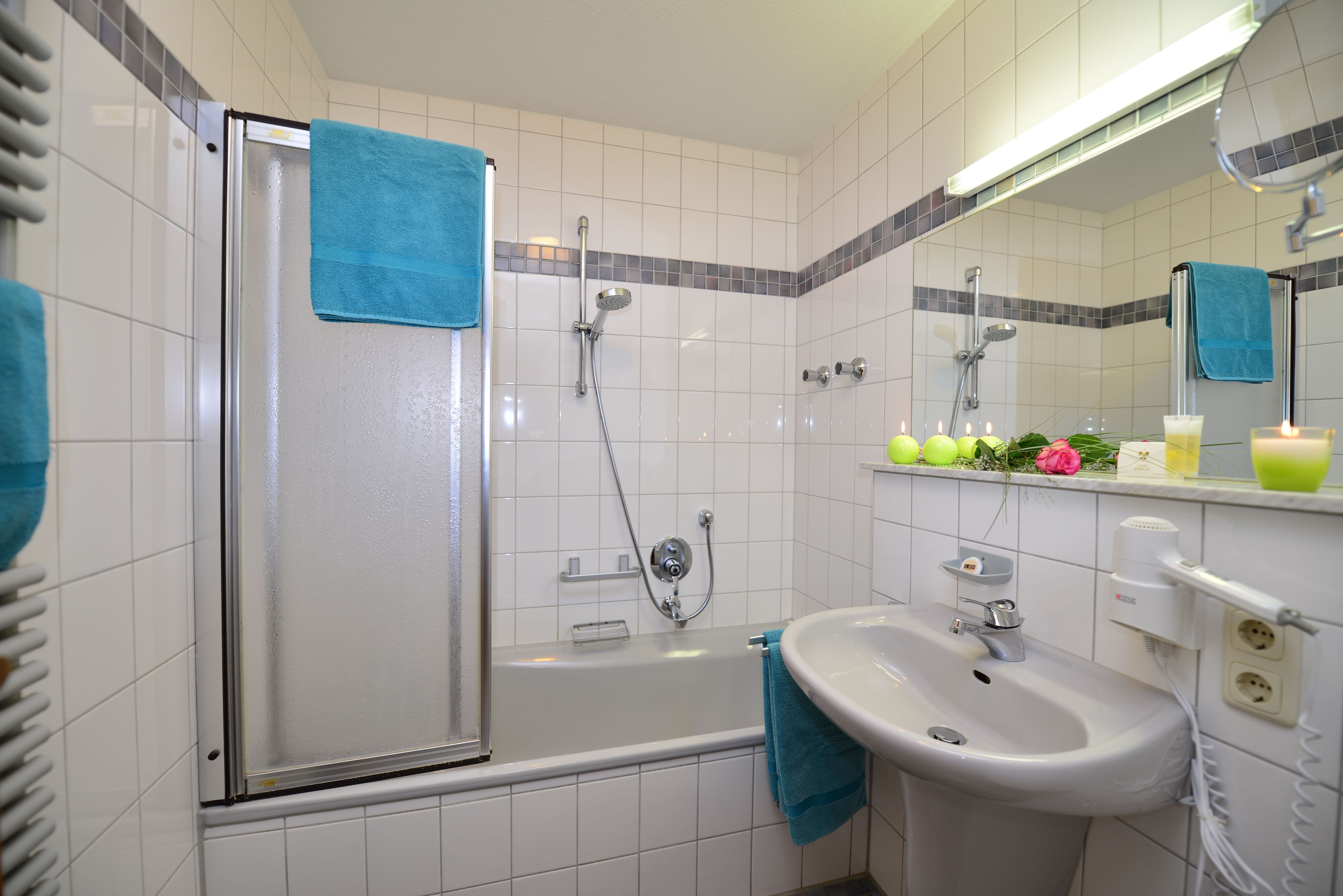 A bathroom with a glass-enclosed shower, a sink, and a mirror.