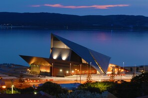 Un bâtiment d’architecture moderne doté d’un design triangulaire unique, situé au bord d’une vaste étendue d’eau.