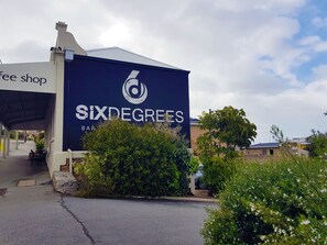 Un edificio con un cartel grande que dice "Six Degrees Bar & Restaurant" y un área de asientos al aire libre techada.