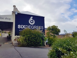 Un edificio con un cartel grande que dice "Six Degrees Bar & Restaurant" y un área de asientos al aire libre techada.