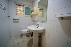 A small, clean bathroom with a toilet, sink, and a window with blinds. - Hanok Hotel Dong Nak Won (Jeonju)