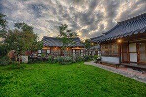 Een traditioneel Koreaans gebouw met een verzorgde tuin en een heldere lucht.
