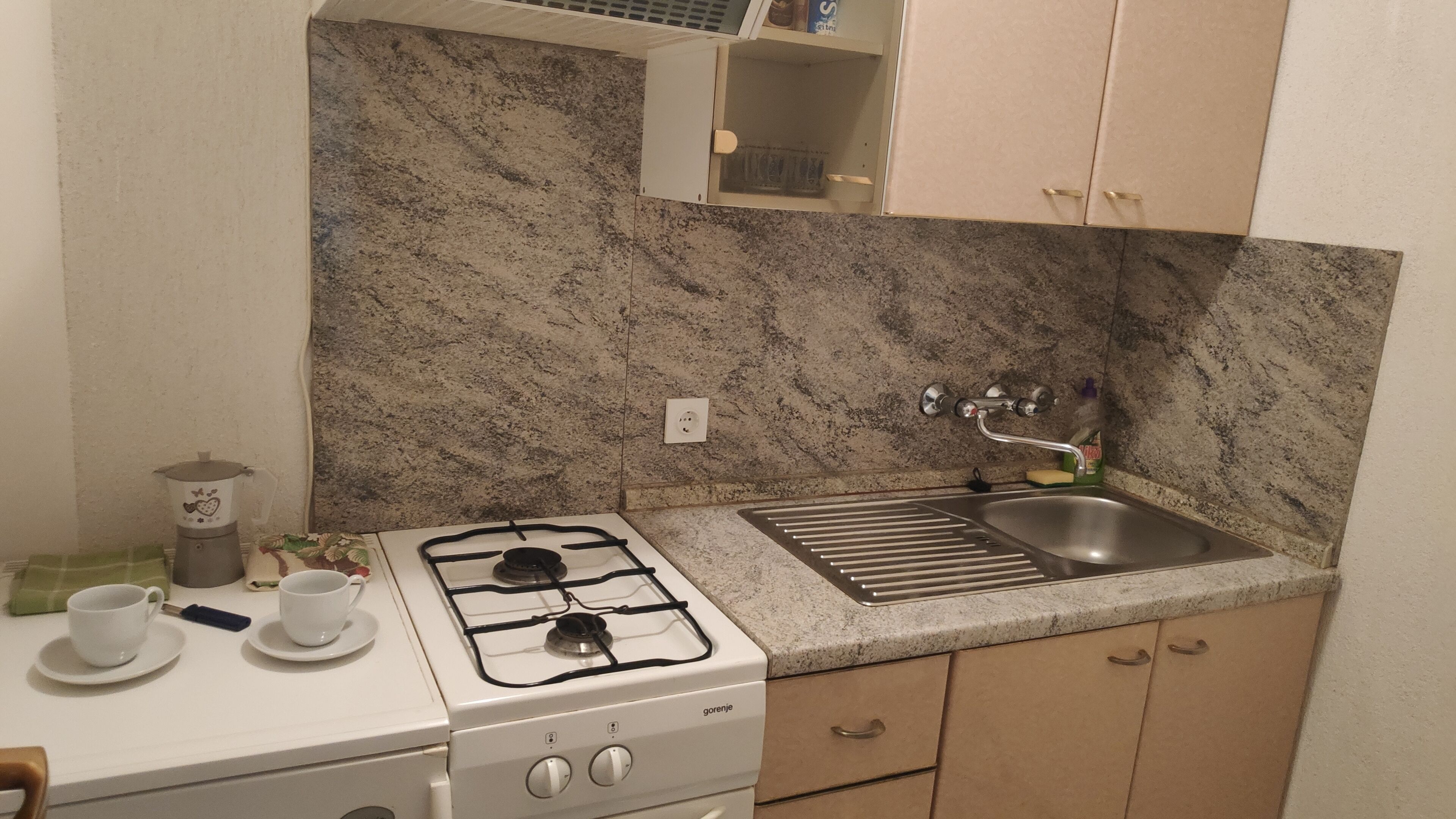 A compact kitchen with a gas stove, a sink, and a small cabinet.