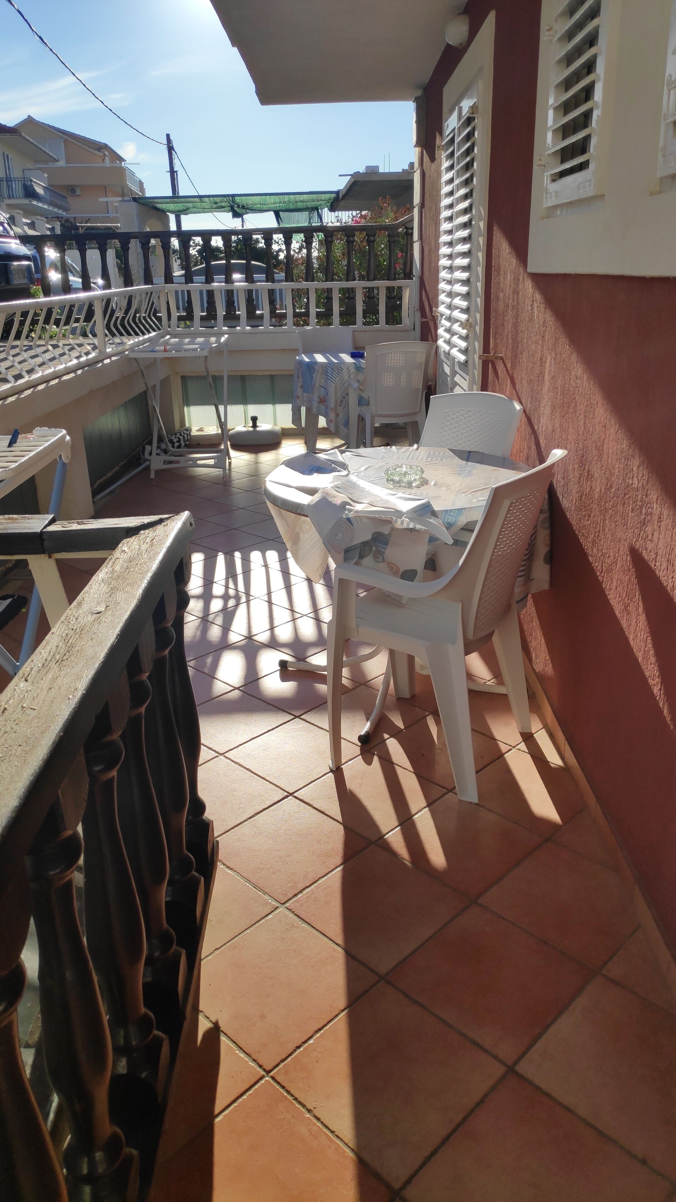 A patio with a table and chairs, a railing, and a view of the street.