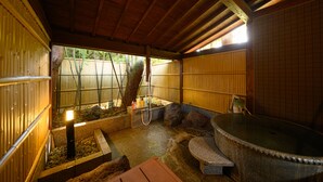 Uma onsen japonesa tradicional com uma nascente de pedra, vigas de madeira e cerca de bambu.
