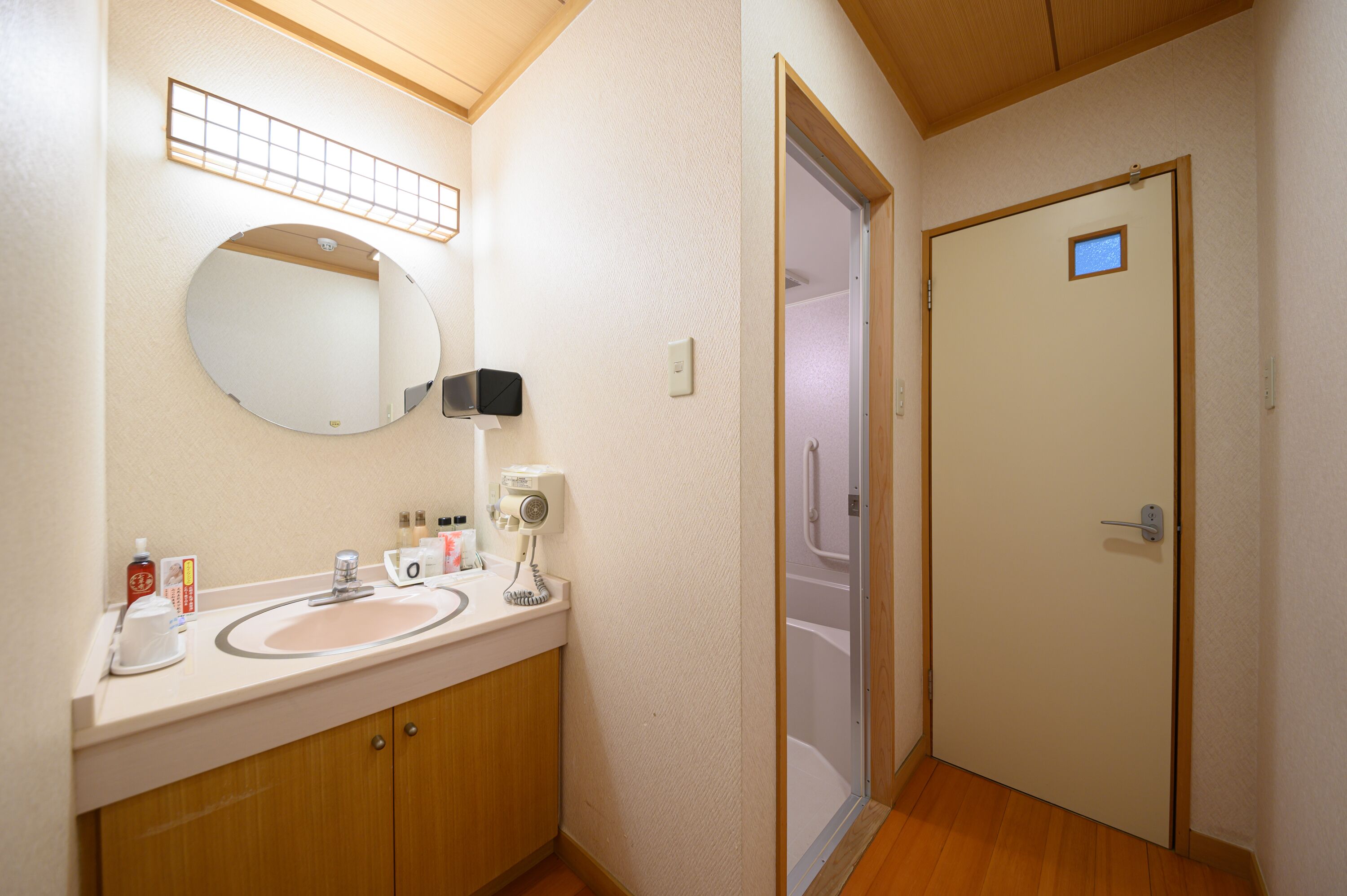 A bathroom with a sink, mirror, and a door leading to a shower.
