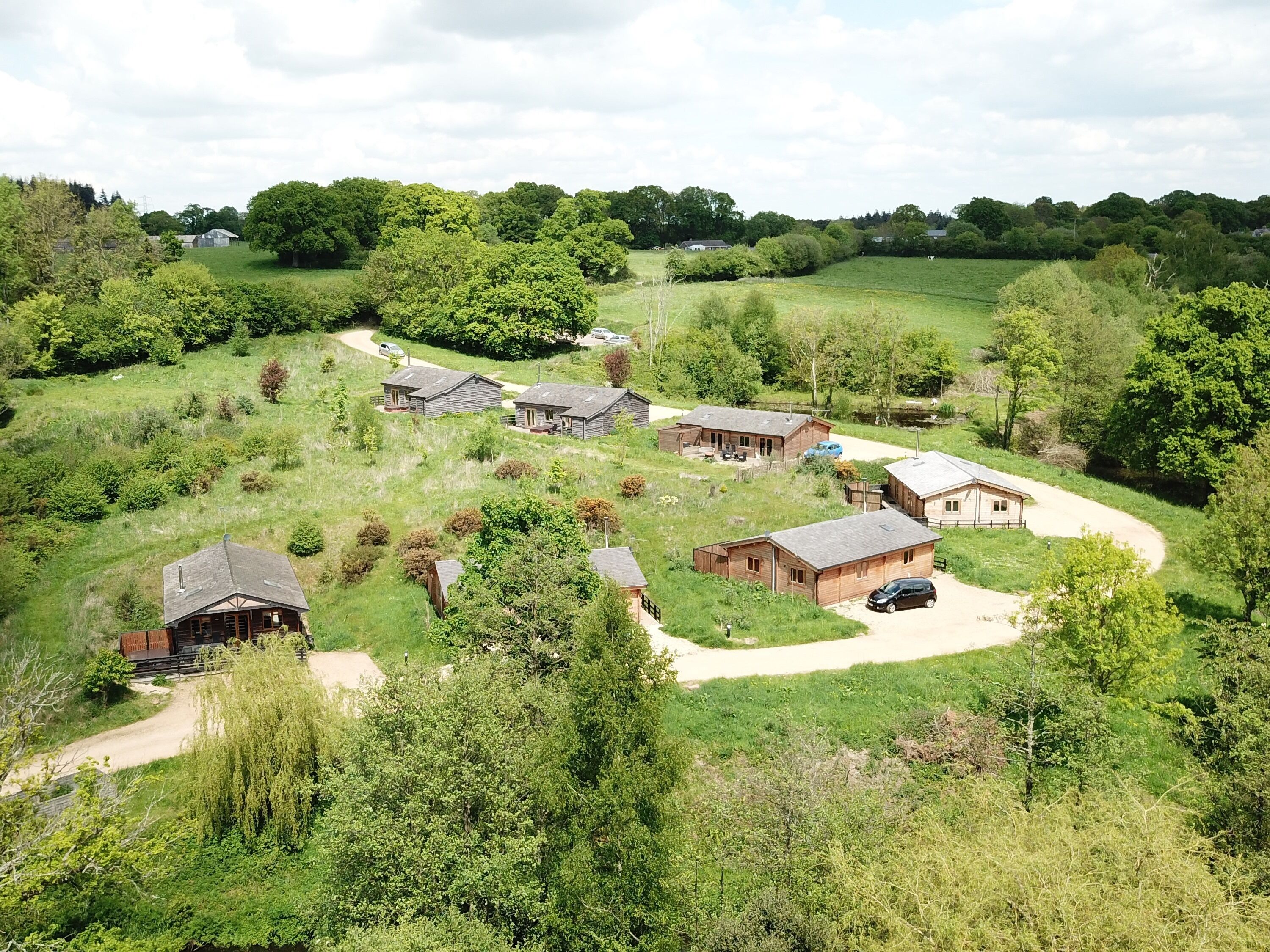 A rural property with several wooden cabins, surrounded by lush greenery and trees.