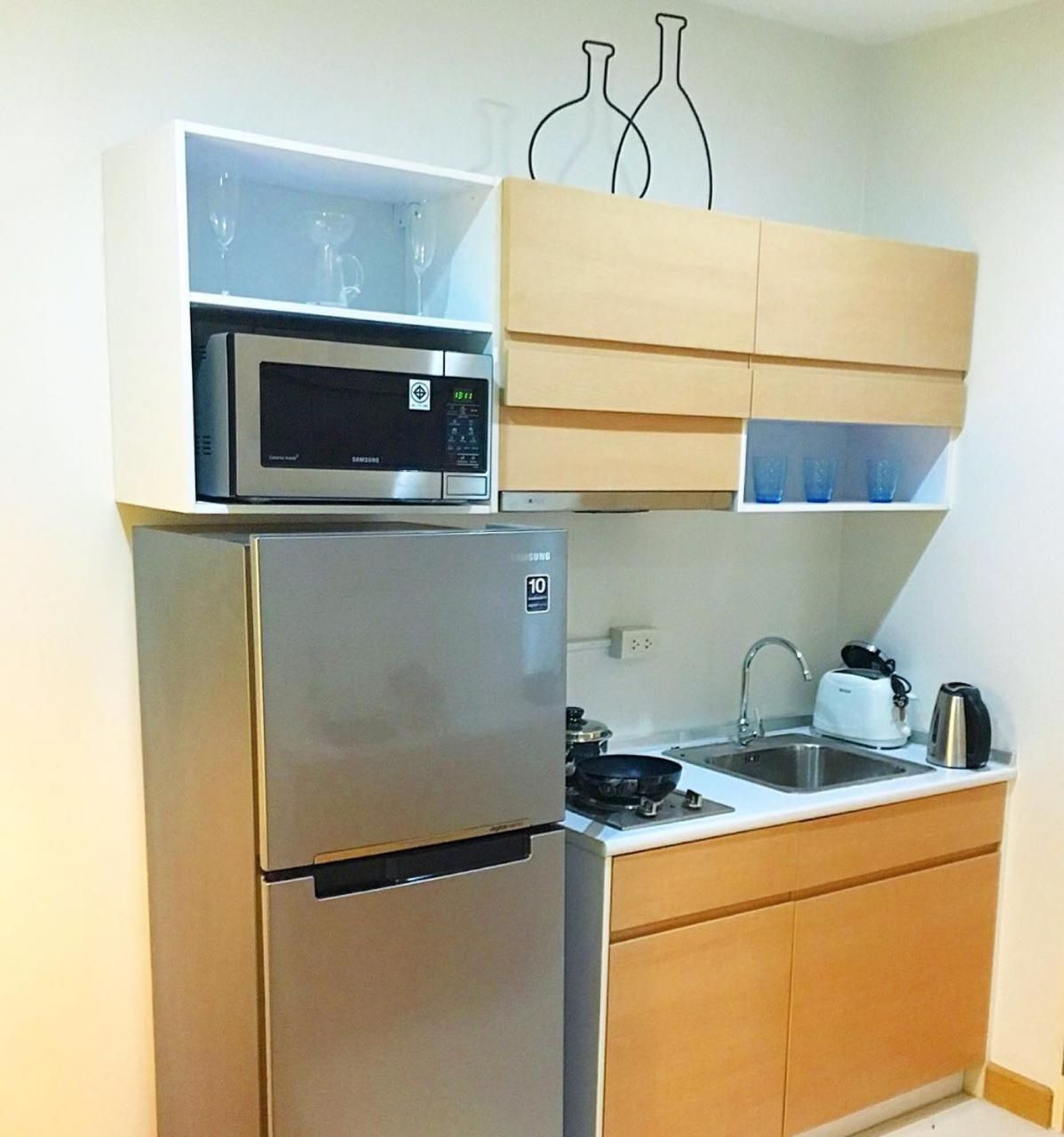 Cocina compacta con refrigerador de acero inoxidable, microondas y tostadora sobre la encimera.