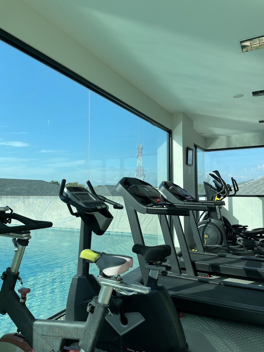 Un gimnasio con equipo de ejercicio y un ventanal que da a una masa de agua.