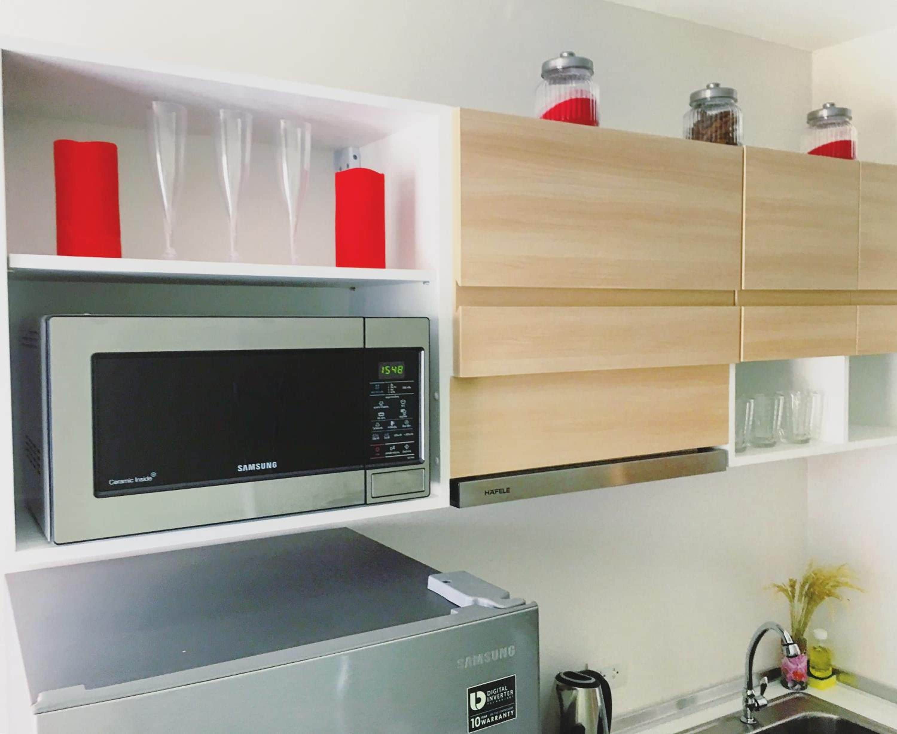 A kitchen with a microwave, a digital clock, and a coffee maker.