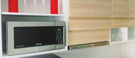 A kitchen with a microwave, a digital clock, and a coffee maker.