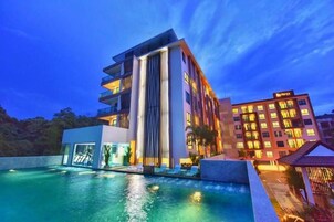 Un hotel moderno con piscina, varios balcones y una fachada bien iluminada.