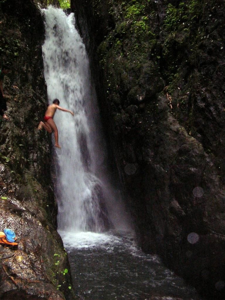 Une cascade avec une personne debout sur un rocher.