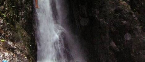 Une cascade avec une personne debout sur un rocher.