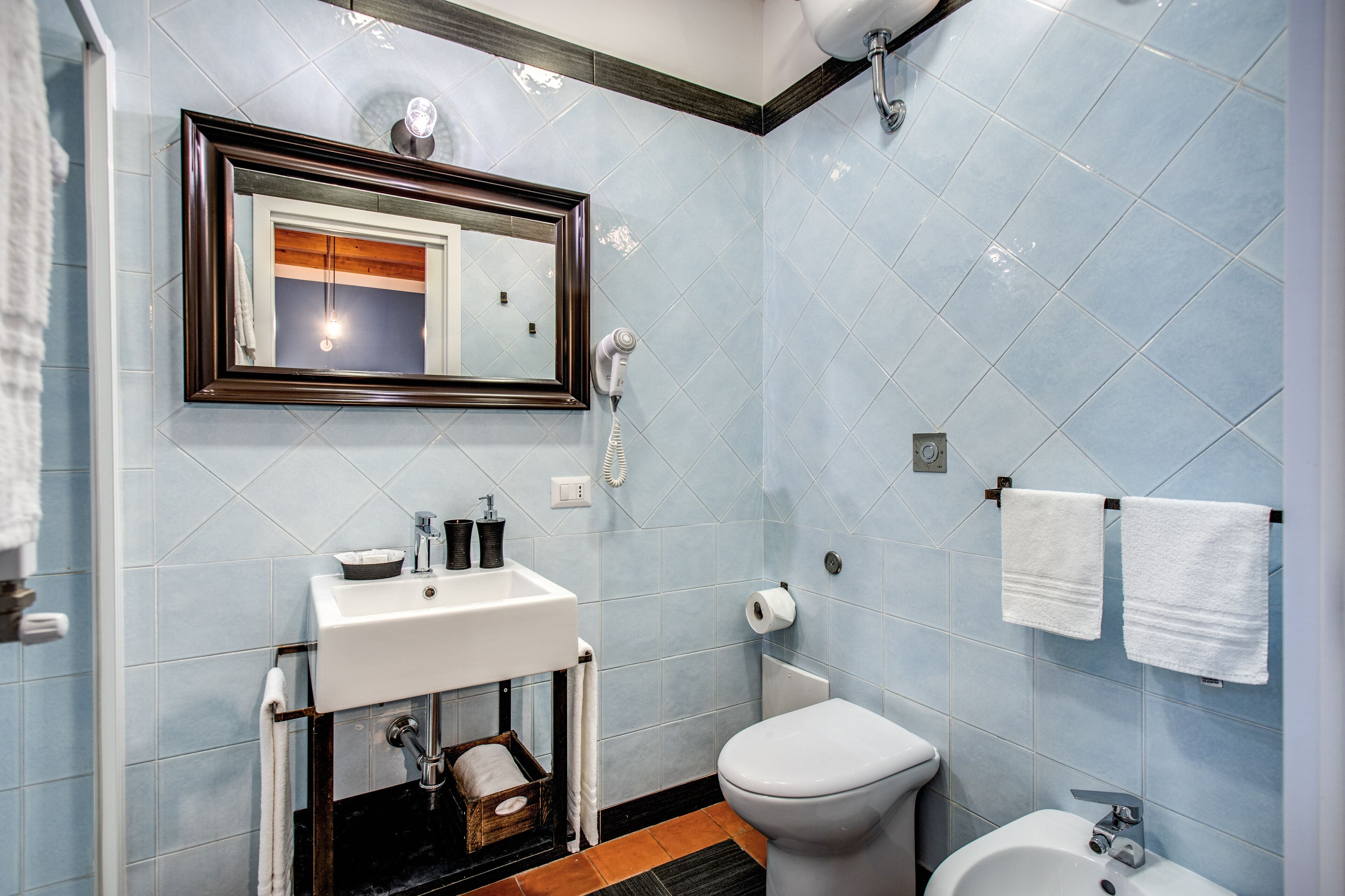A bathroom with a sink, toilet, bidet, and a mirror.