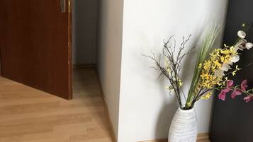 Une porte en bois avec une plaque nominative, un vase blanc rempli de fleurs et un plancher en bois.
