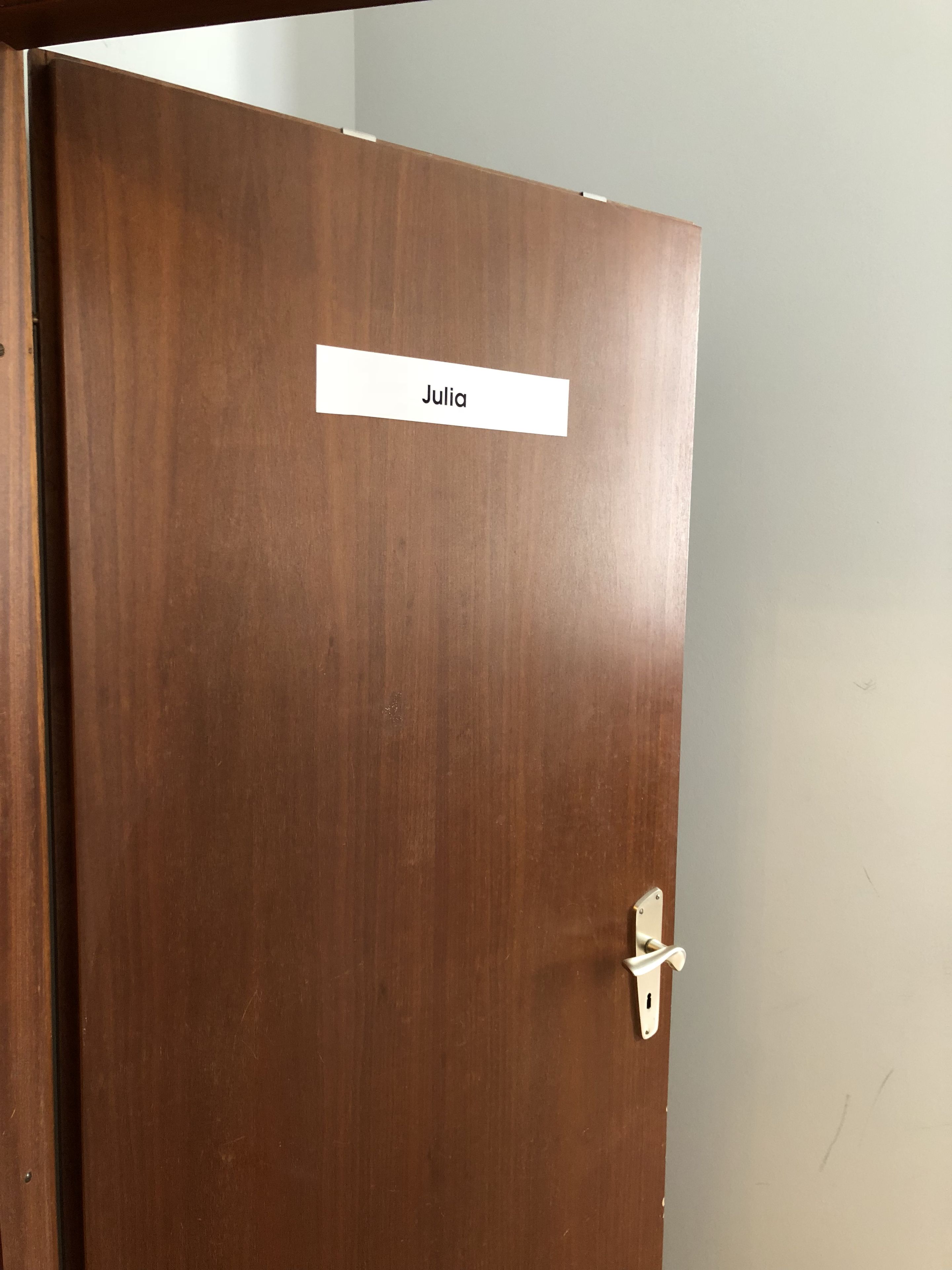Eine geschlossene Holztür mit einem Schild mit dem Namen Julia und einer schlichten Riegelverriegelung.
