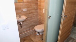 Een compacte badkamer met wastafel, toilet en douchehoek.