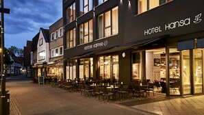 A hotel with a modern facade, outdoor seating area, and a visible sign for 'Hotel Hansa'. - Hotel Hansa (Herford)